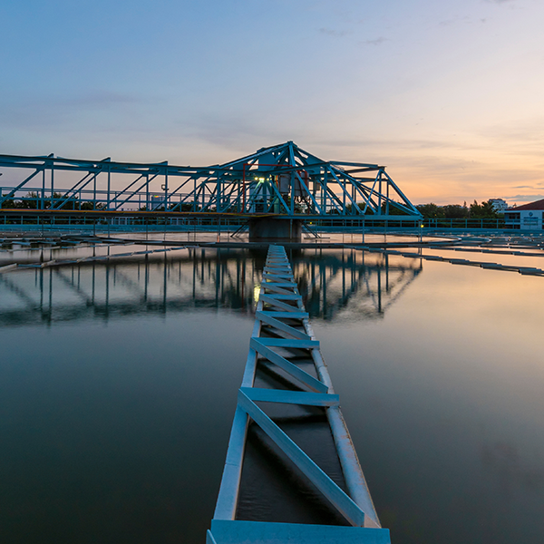 A blue truss structure at the Quincy Water Reuse Utility captured in soft lighting at dawn. The structure rests over water and casts a reflection on the surface. A blue truss structure at the Quincy Water Reuse Utility captured in soft lighting at dawn. The structure rests over water and casts a reflection on the surface.