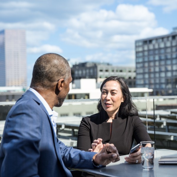 Male and female corporate office workers in suits sitting on a rooftop deck.