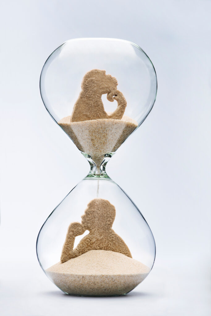An hourglass with a primate in the top half and a man in the bottom