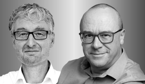 Two people side by side, Max Welling on the left and Chris Bishop on the right, in black and white smile and look forward.