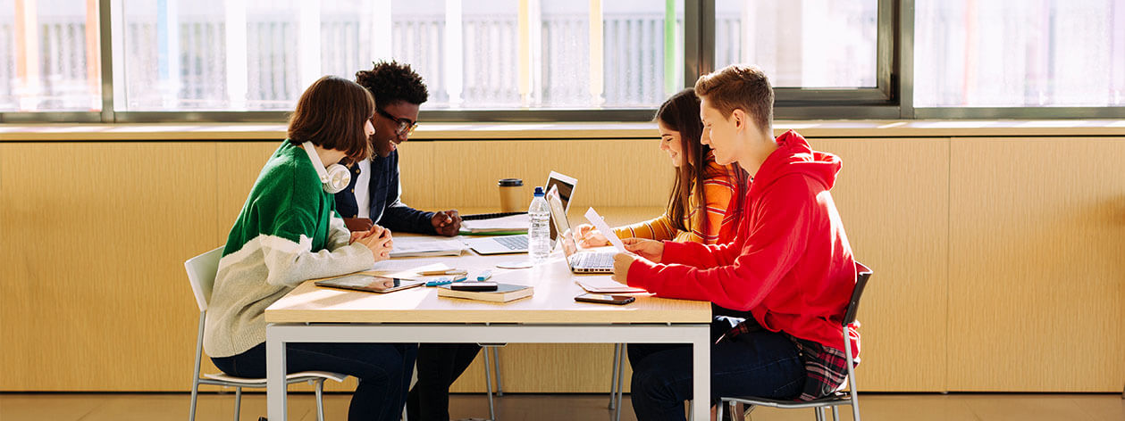 Four students sitting at a table studying and talking